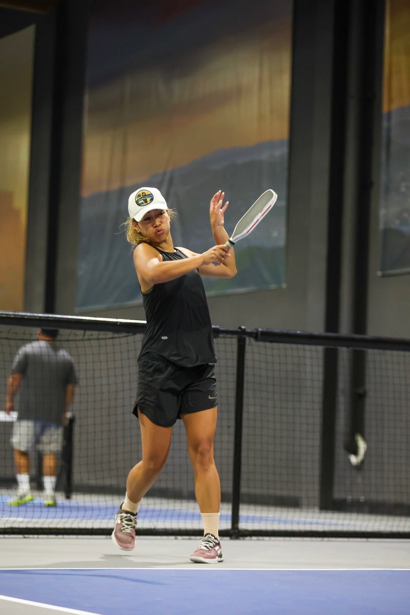 Woman wearing white Taupou foam trucker hat by Siva Vibe while playing pickleball — combining island culture with active lifestyle