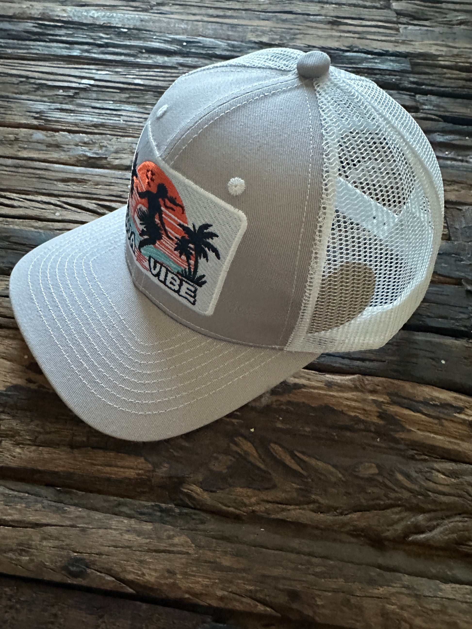 Side view of Siva Vibe gray cotton trucker hat with embroidered logo — relaxed fit and breathable mesh back